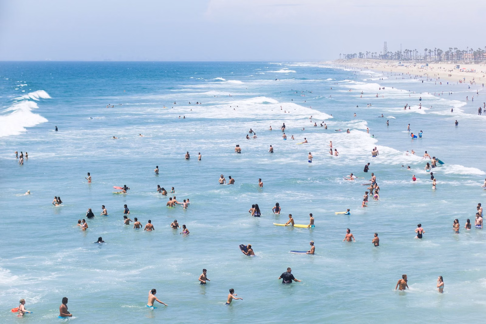 Swimmers in the surf along the sandy Huntington Beach coastline in Orange County, California, on a sunny day