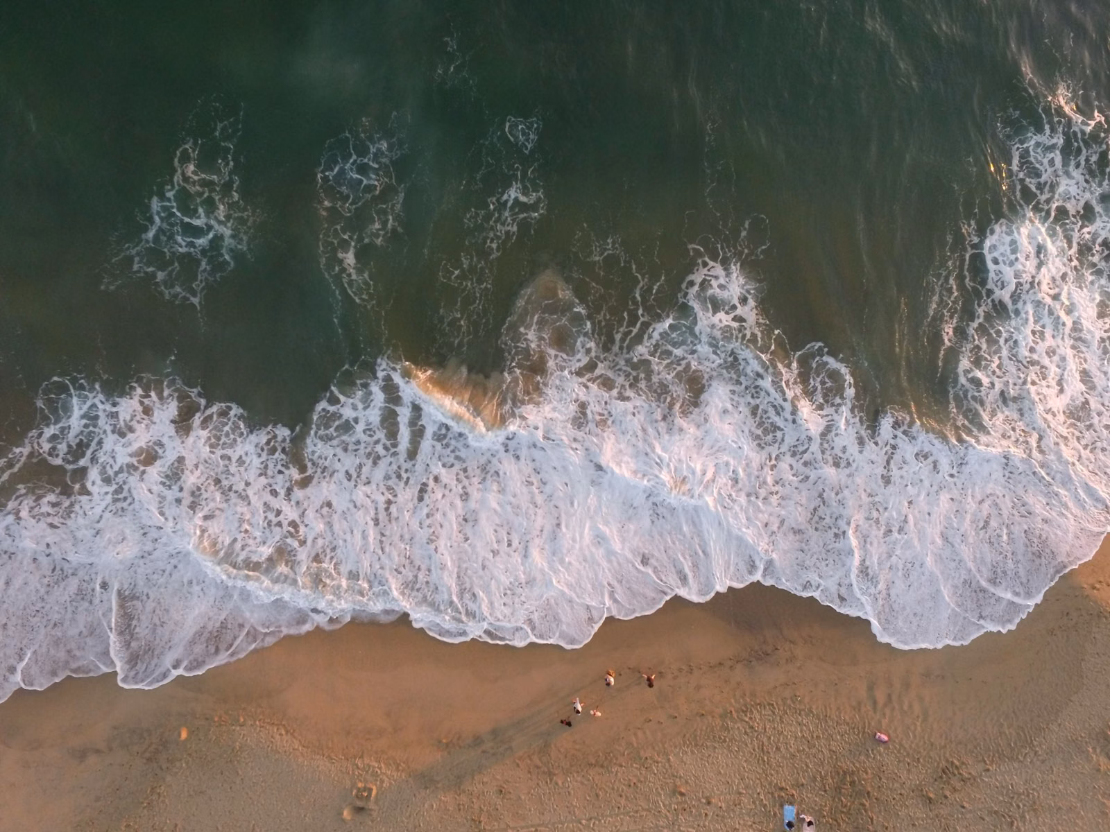 Aerial view of white surf breaking onto a sandy Southern California beach