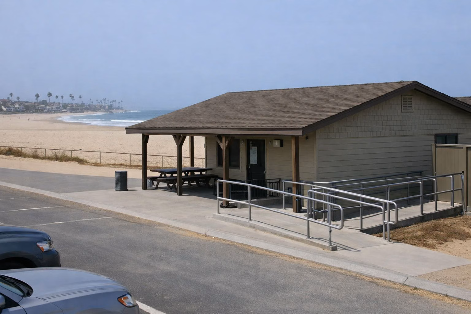 A small single-story beach visitor center with a shaded porch and ramp near the sand